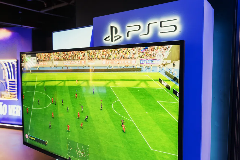 A games console and controller set up beside a television