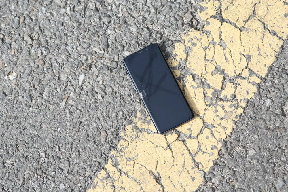 A damaged phone lying face-up on wet ground