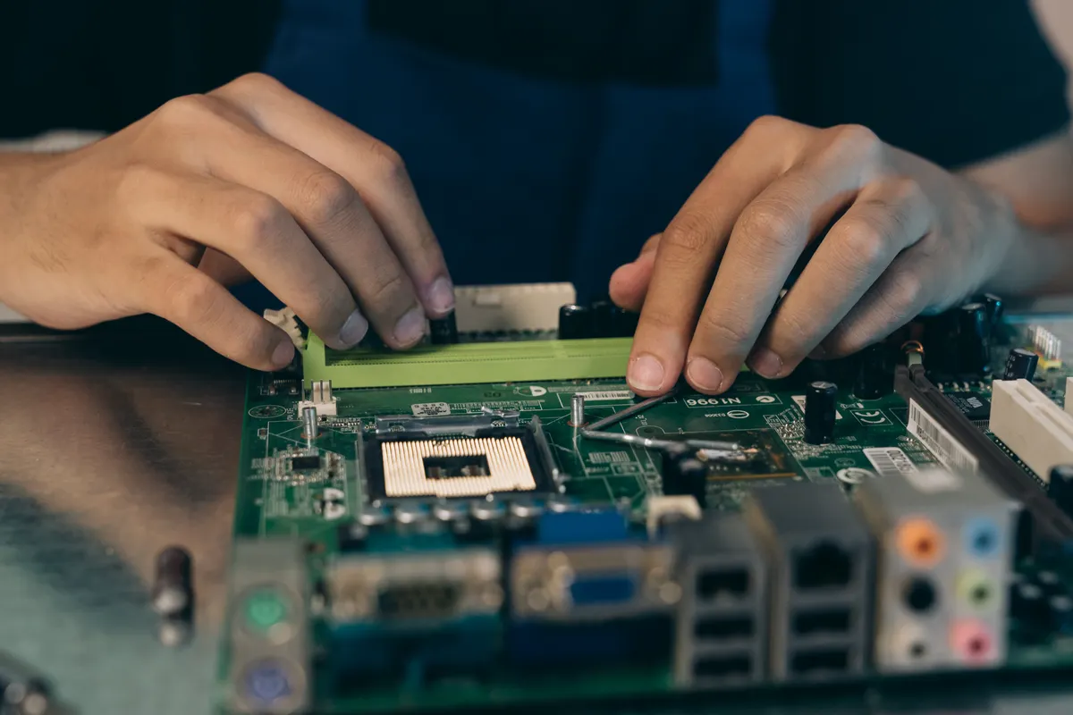 Close-up of a technician working on a circuit board with tweezers