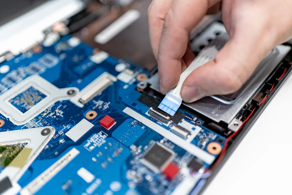 A technician working on the inside of an open laptop
