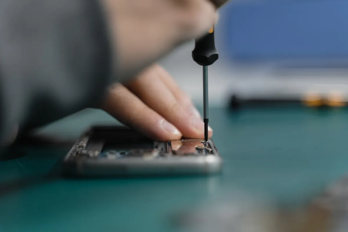 A technician opening a smartphone with a precision screwdriver