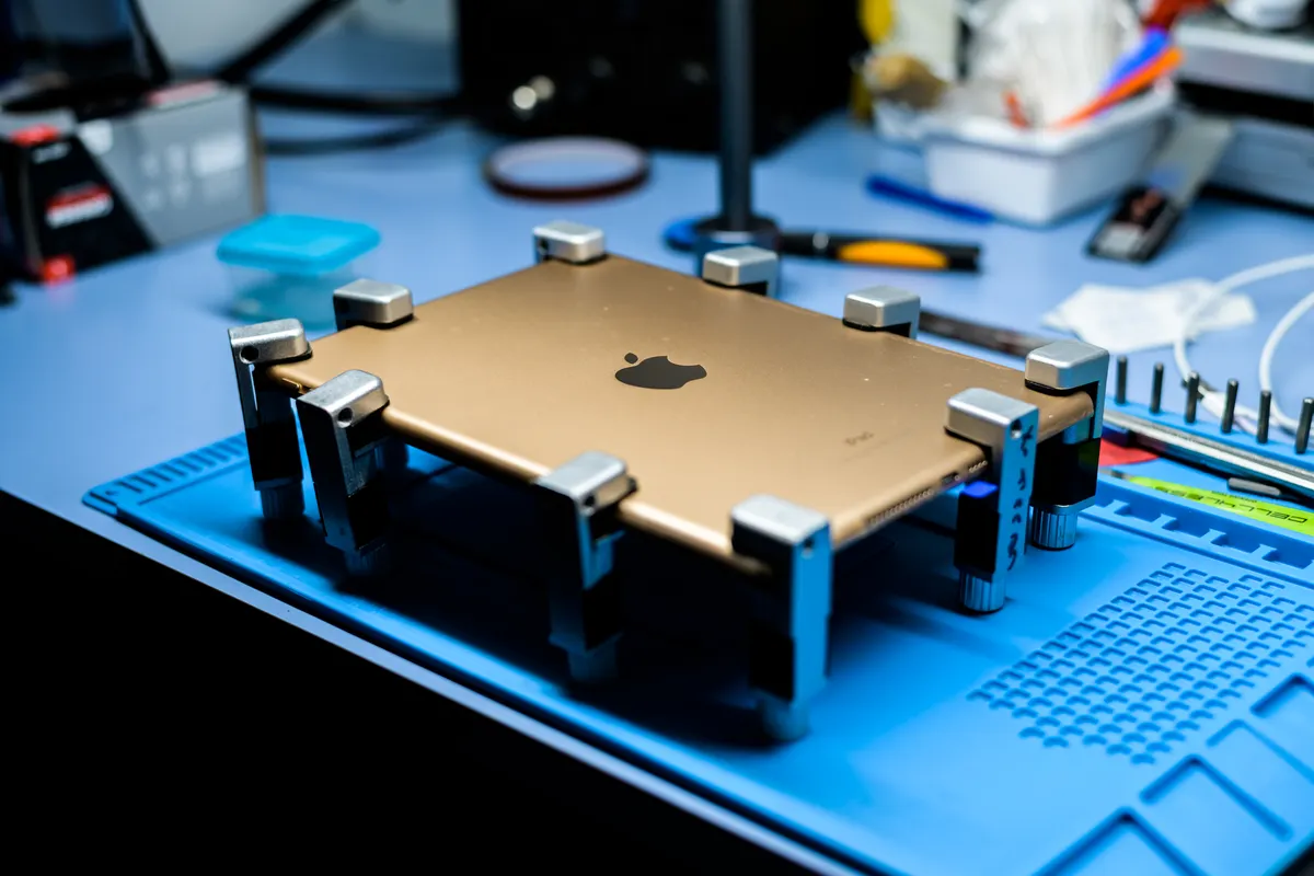 A tablet opened for repair on a workshop bench